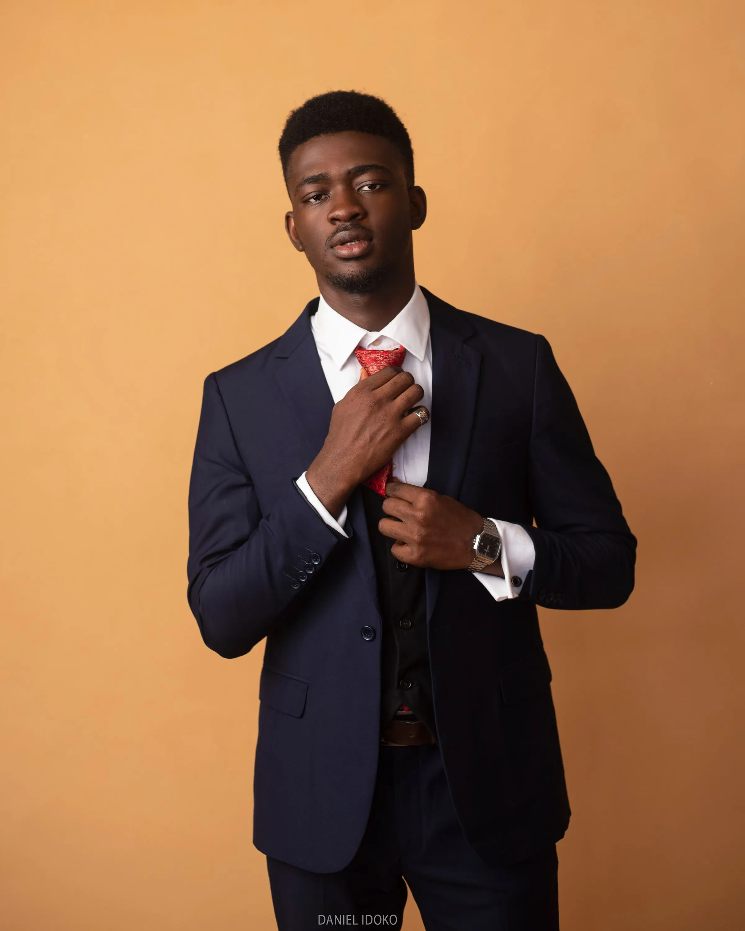 Samuel Odifa in a navy suit, adjusting his tie